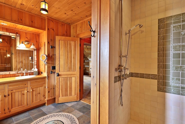 bathroom featuring wooden ceiling, vanity, a tile shower, and wooden walls