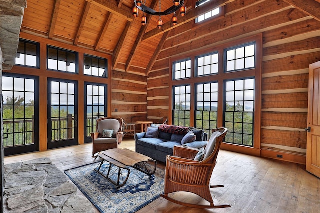 interior space with light hardwood / wood-style floors, beamed ceiling, wooden walls, wood ceiling, and high vaulted ceiling