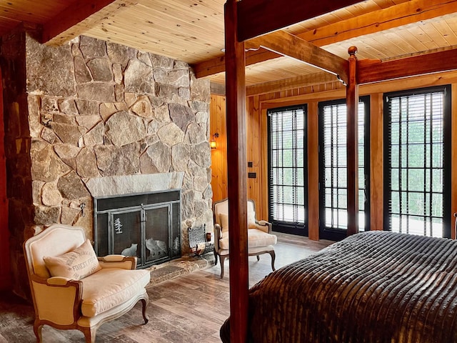 bedroom featuring hardwood / wood-style flooring, wooden ceiling, beam ceiling, and a stone fireplace