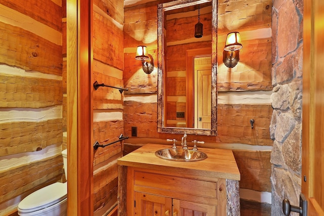 bathroom featuring toilet, vanity, and wooden walls