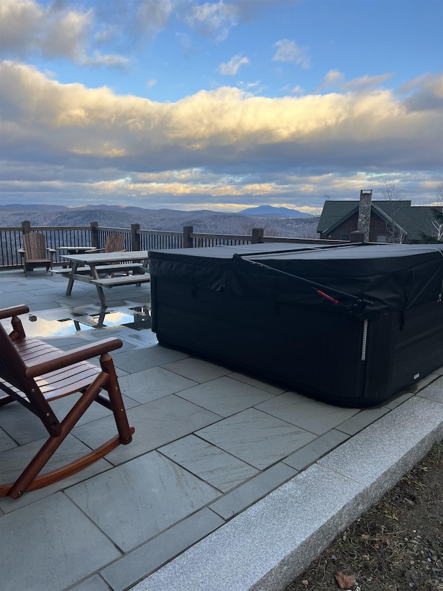 patio terrace at dusk featuring a mountain view and a hot tub