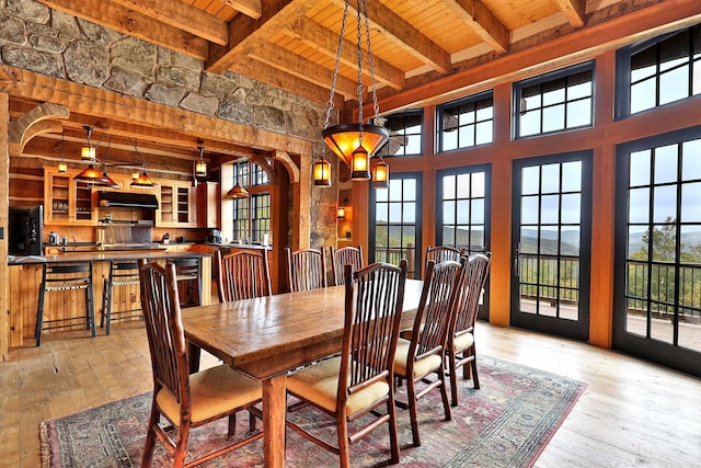 dining room featuring wood ceiling, light hardwood / wood-style floors, plenty of natural light, and beamed ceiling