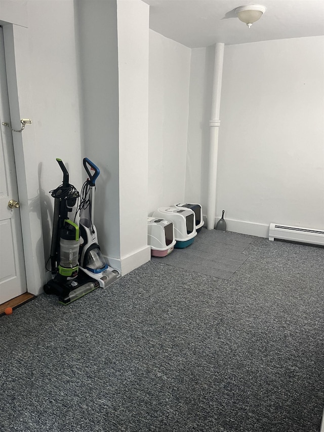 misc room with a baseboard heating unit and dark colored carpet