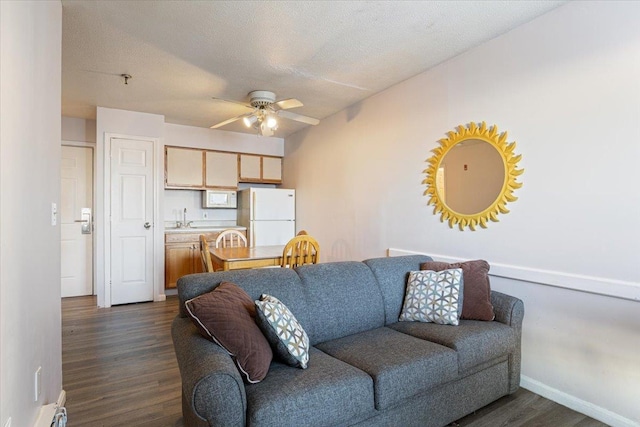 living room featuring ceiling fan, a baseboard heating unit, dark hardwood / wood-style floors, and a textured ceiling