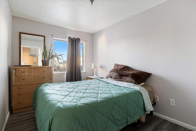 bedroom with dark hardwood / wood-style floors and a textured ceiling