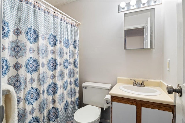 bathroom featuring toilet, a shower with shower curtain, and vanity