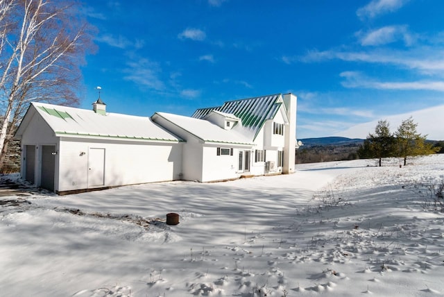 snow covered back of property with a garage and a mountain view