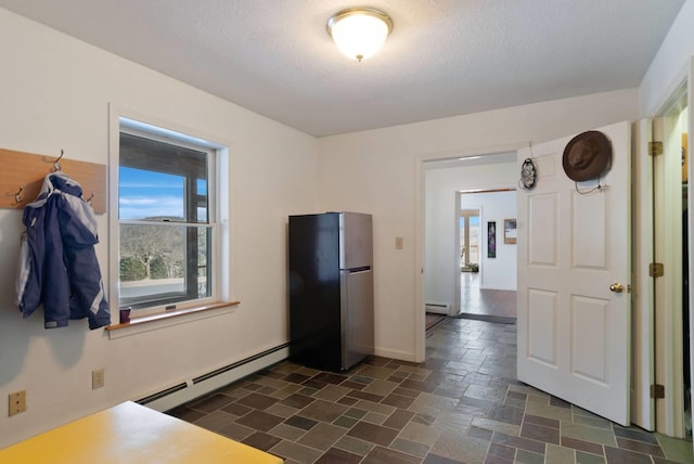 kitchen with stainless steel refrigerator, a baseboard radiator, and a textured ceiling