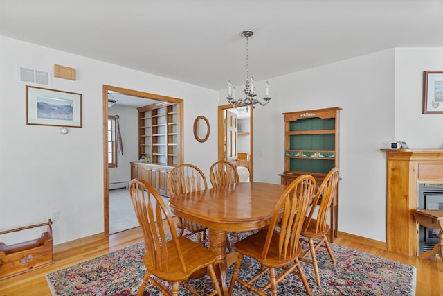 dining space featuring baseboard heating, a chandelier, and light wood-type flooring