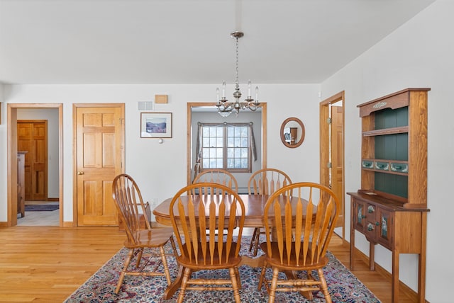 dining room with a notable chandelier and light wood-type flooring