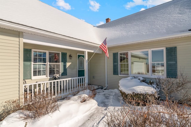 snow covered property entrance with a porch