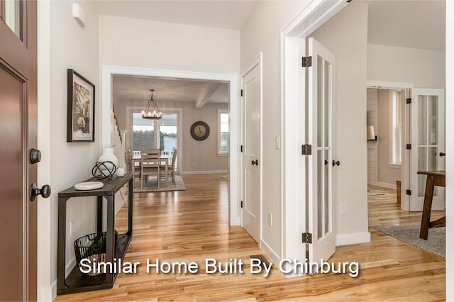 corridor with hardwood / wood-style floors and a notable chandelier