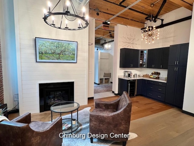 living room featuring light hardwood / wood-style flooring, beam ceiling, wood ceiling, a large fireplace, and beverage cooler