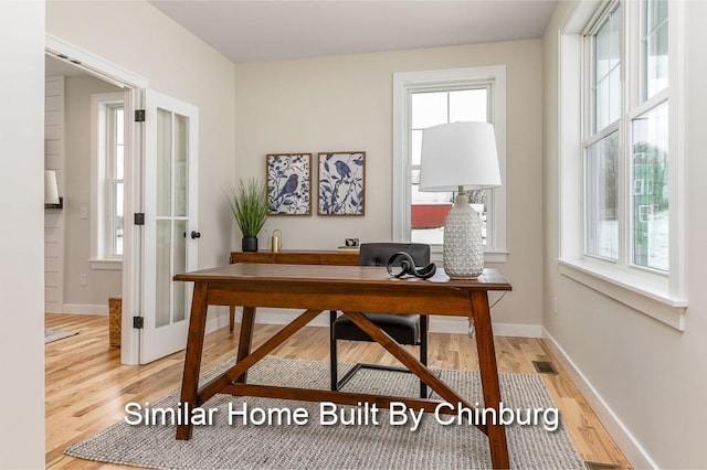 office area with light hardwood / wood-style floors and a healthy amount of sunlight