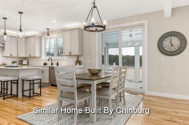 dining space featuring sink, a wealth of natural light, an inviting chandelier, and light wood-type flooring