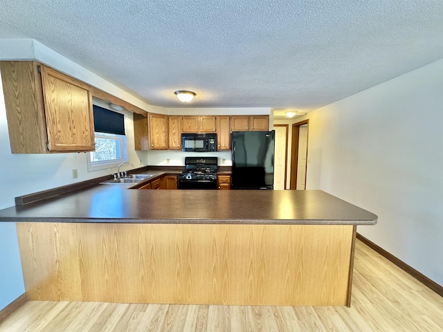 kitchen featuring kitchen peninsula, black appliances, light hardwood / wood-style flooring, and sink