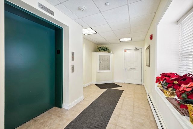 corridor with elevator, a baseboard heating unit, and a drop ceiling