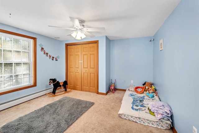 bedroom with a closet, ceiling fan, light colored carpet, and baseboard heating