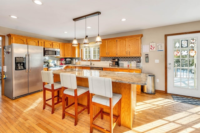 kitchen featuring sink, stainless steel appliances, a kitchen island, and a healthy amount of sunlight