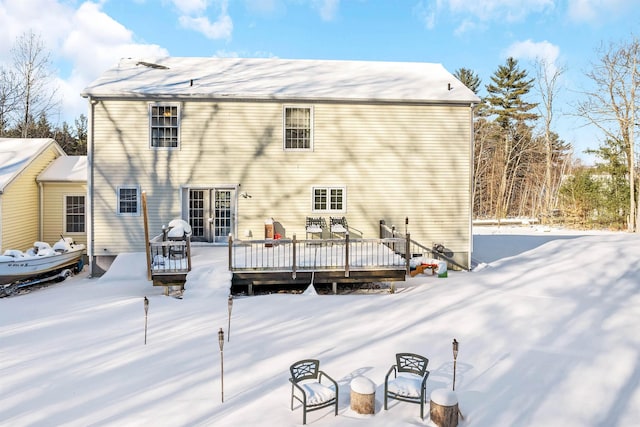 snow covered back of property featuring a deck