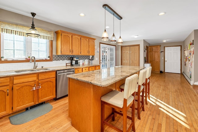 kitchen with sink, a kitchen island, pendant lighting, and stainless steel dishwasher