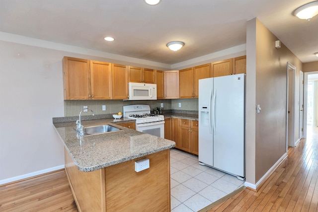 kitchen featuring sink, white appliances, kitchen peninsula, and tasteful backsplash