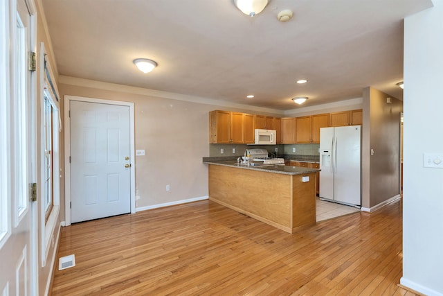 kitchen featuring dark stone counters, white appliances, kitchen peninsula, and light hardwood / wood-style floors