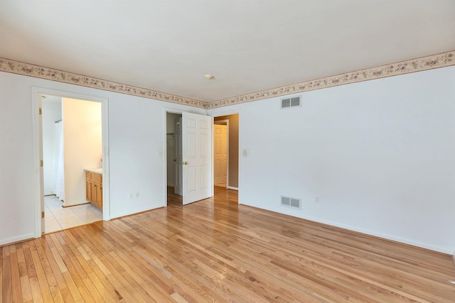 unfurnished bedroom with light hardwood / wood-style floors and ensuite bathroom