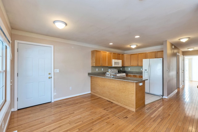 kitchen featuring light hardwood / wood-style floors, backsplash, white appliances, and kitchen peninsula