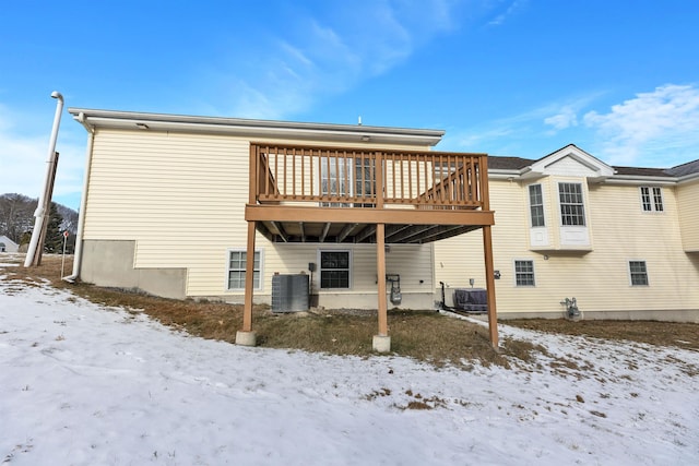 snow covered back of property featuring a wooden deck and cooling unit