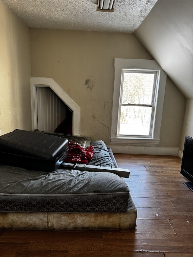 bedroom featuring hardwood / wood-style floors, a textured ceiling, and lofted ceiling