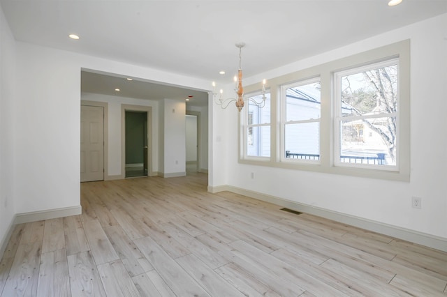 unfurnished dining area with a chandelier and light hardwood / wood-style floors