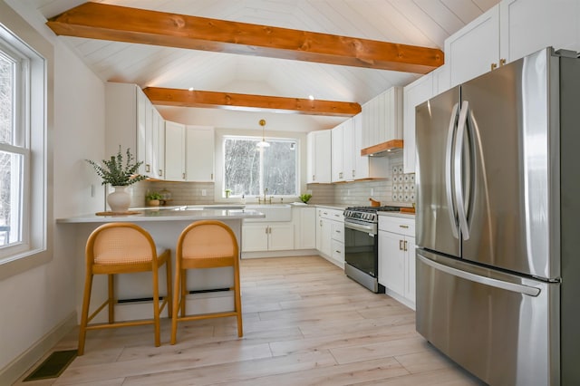 kitchen with white cabinets, appliances with stainless steel finishes, and lofted ceiling with beams