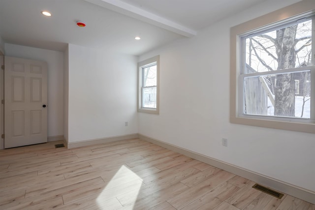 spare room featuring light hardwood / wood-style flooring and beam ceiling