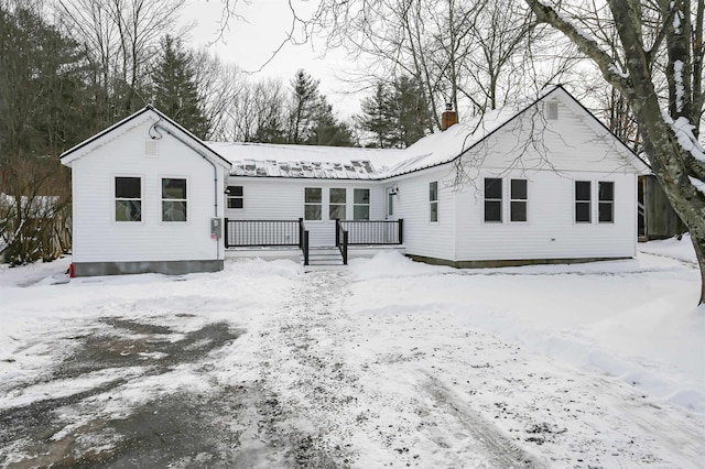 snow covered rear of property with a deck