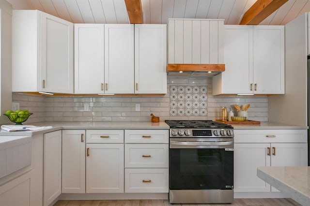 kitchen featuring white cabinetry, stainless steel gas range, decorative backsplash, and light stone counters