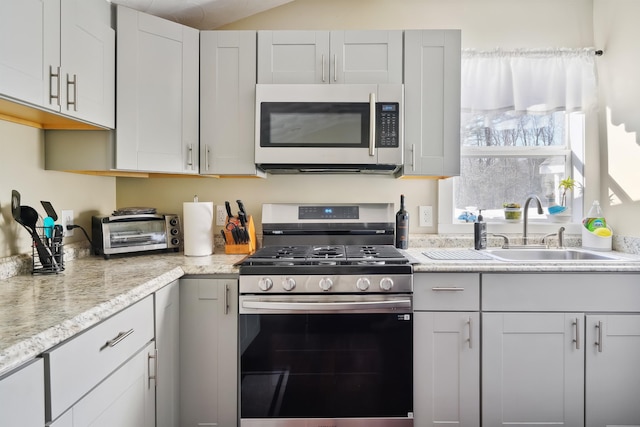 kitchen with sink, light stone counters, white cabinets, and appliances with stainless steel finishes