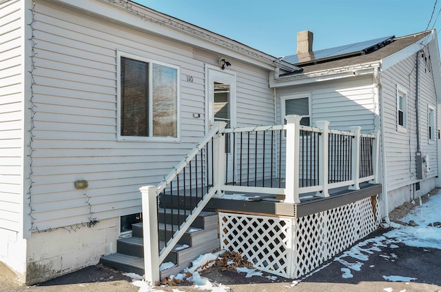 snow covered property entrance with solar panels