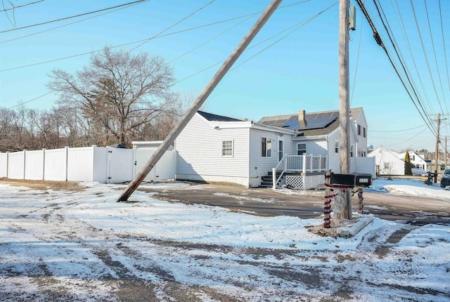 snow covered back of property featuring solar panels