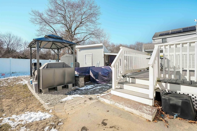 snow covered deck with a gazebo and a storage shed