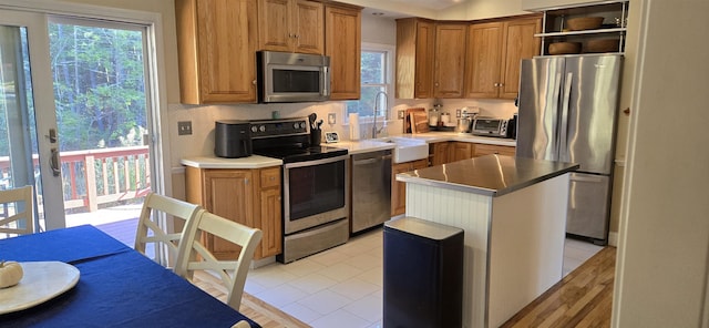 kitchen featuring sink, stainless steel appliances, a kitchen island, and a wealth of natural light