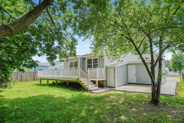 back of house featuring a patio area, a lawn, and a wooden deck