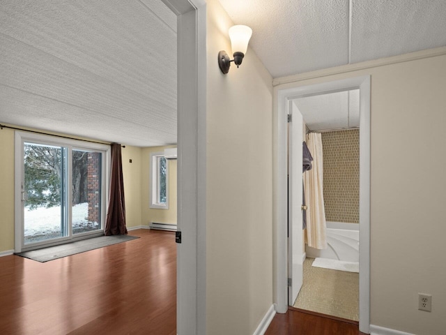 hall with a baseboard heating unit, dark wood-type flooring, and a textured ceiling