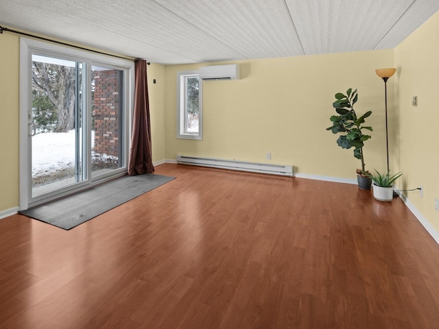 unfurnished room with a baseboard heating unit, a wall mounted air conditioner, and hardwood / wood-style floors