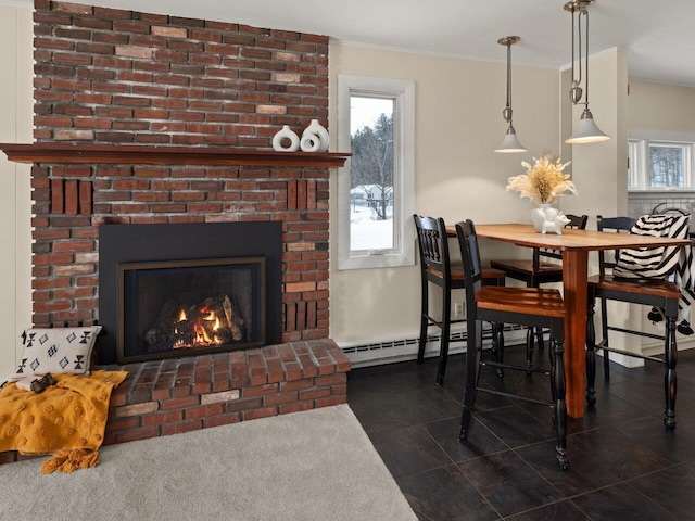 dining room featuring ornamental molding, a brick fireplace, and a baseboard heating unit