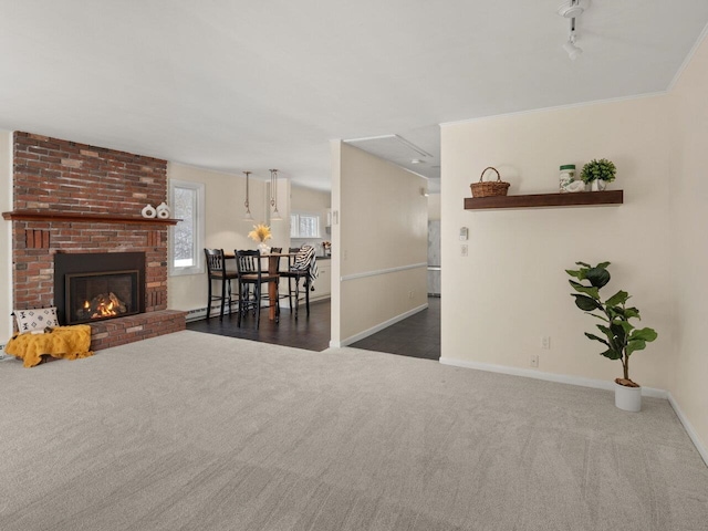 living room with dark colored carpet, a fireplace, ornamental molding, track lighting, and a baseboard radiator