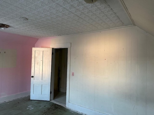 unfurnished room featuring vaulted ceiling and wooden walls