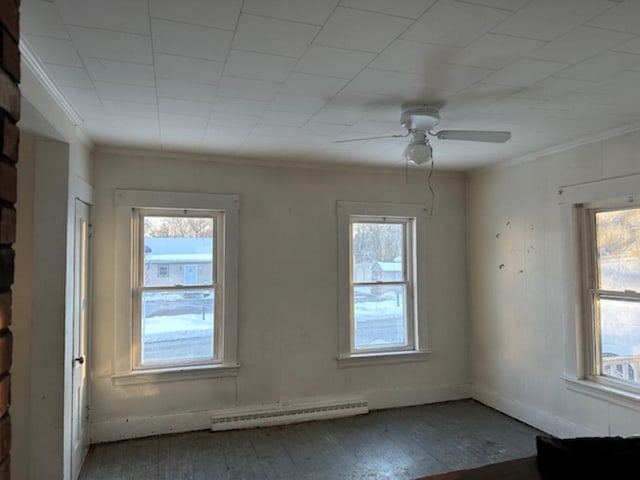 empty room featuring hardwood / wood-style flooring, a baseboard heating unit, plenty of natural light, and crown molding