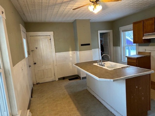 kitchen featuring ceiling fan, sink, and an island with sink