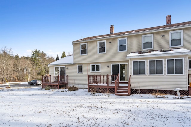 snow covered rear of property with a deck